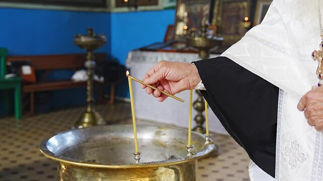 without a face. The priest lights candles on the baptismal font for baptism in the church. Orthodox Faith and Traditions.