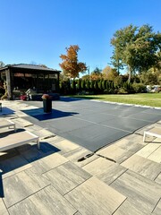 Winterized J-shaped built-in, inground pool with safety Loop - Loc mesh cover to protect it. ...