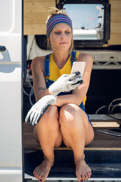 Young woman wearing blue bandana and white gloves playing on her cellphone