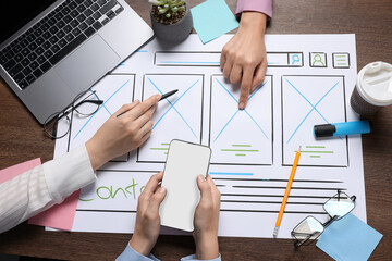 Developing UI design. Designers creating website wireframe on paper at wooden table, top view