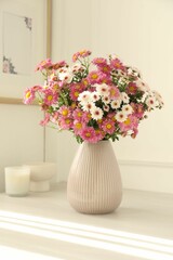 Beautiful flowers in vase and decor on white table at home