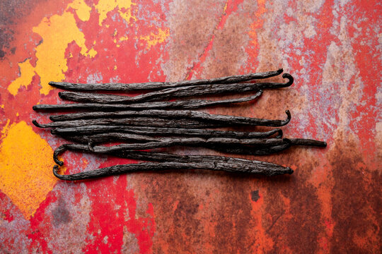 Vanilla beans on colorful metal surface 