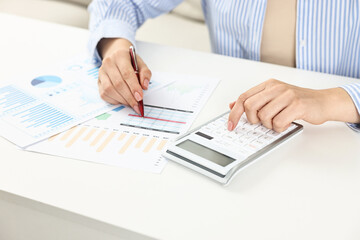 Fototapeta premium Budget planning. Woman with papers using calculator at white table, closeup