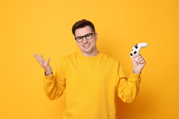Unhappy young man with controller on orange background © New Africa