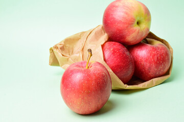 Red apples and in a kraft paper bag. Green background and copy space.