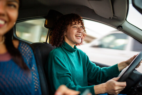 Smiling woman driving car with friend in passenger seat