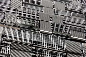 The wall of a modern building with randomly arranged metal louvers of various designs and sizes