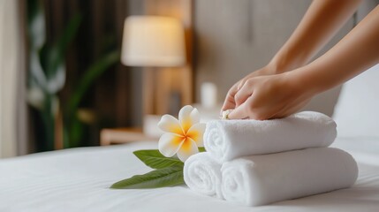 Organizing fresh towels with a fragrant flower in a tranquil hotel room during the day