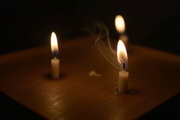 Burning candles in dark room with slight smoke from extinguished candle. Concept of silence, meditation, and peace