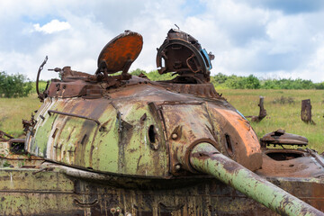 Old destroyed Russian tank on a grassy field