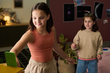 Two young girls happily engaging with each other while standing in a cozy, well-decorated room creating a warm and joyful atmosphere