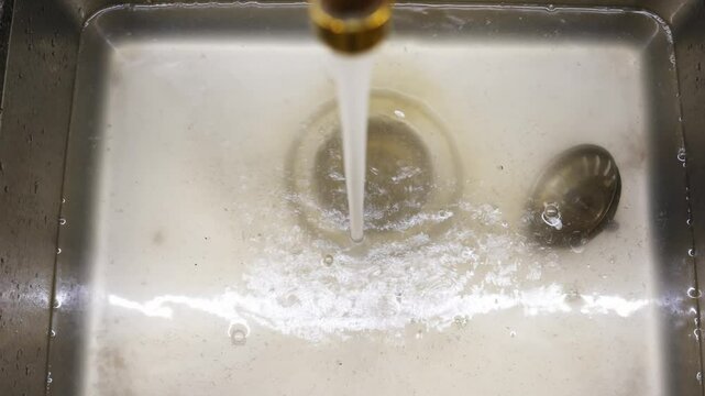 A clogged metal kitchen sink. Water does not drain into the water supply due to blockage.