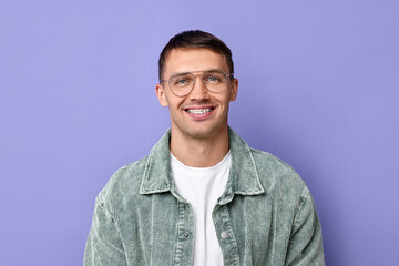 Fototapeta premium Smiling man with dental braces on violet background