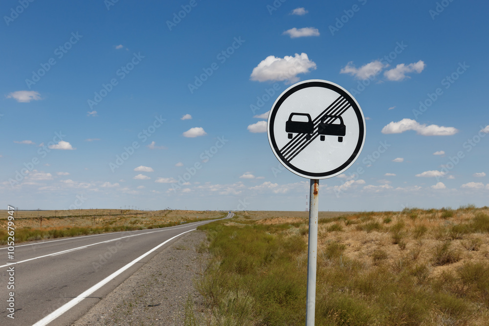 Wall mural traffic sign on a road in the middle of the steppe. road sign end of no overtaking zone. kazakhstan