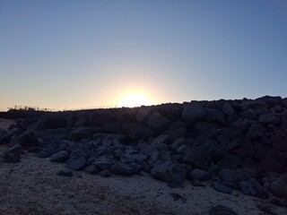 Hazy beautiful indigo blue sunset over large beach rocks and stones on an english shoreline south...