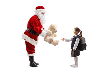 Full length profile shot of Santa Claus giving a teddy bear to a pupil
