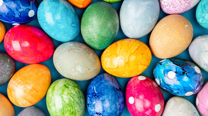 Different easter eggs on wooden plate on green table
