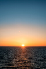 Fototapeta premium Baltic sea at sunset. Clear sky with glowing golden sun, reflections in the water. Setting sun. Epic seascape. Abstract natural pattern, texture, background, concept image