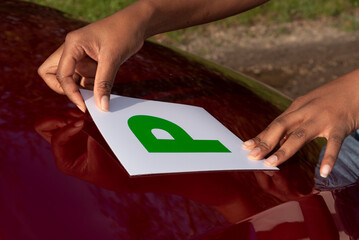 Hampshire England UK. 27.10.2024. Advisory gree P plate being positioned on car bonnet. Test pass withinn one year, a new driver.