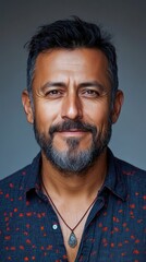 Obraz premium Portrait of a man with a beard and a necklace, smiling against a gray background