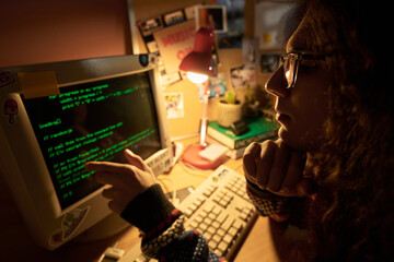 Young programmer engrossed in coding on an old-style computer in a cozy, warmly lit home office setting filled with various retro decorations and a desk lamp