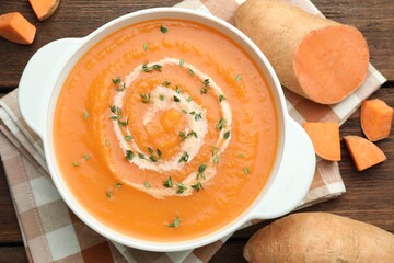 Delicious sweet potato soup with microgreens and fresh vegetables on wooden table, flat lay
