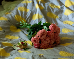 bouquet of pink roses and cake on the bed