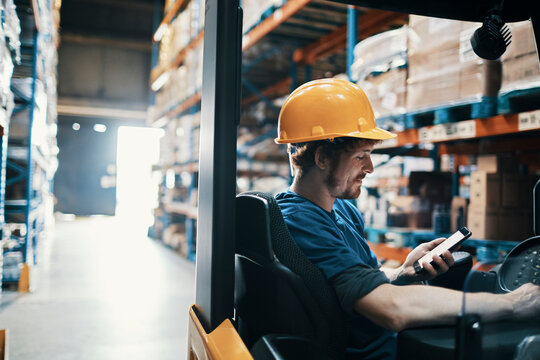 Warehouse forklift driver using smartphone during work