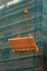 Large Concrete Debris on Crane Hook: Construction Site Scene with Scaffolding