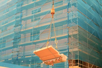 Large Concrete Debris on Crane Hook: Construction Site Scene with Scaffolding