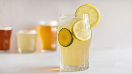 Fototapeta premium A glass of lemonade with a slice of lemon on top. The glass is on a table with other glasses and a bottle