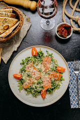 Arugula salad with smoked salmon, cherry tomatoes, and freshly grated Parmesan, served with red wine