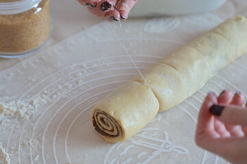 Close-up a woman hands cuts a twisted dough with a thread on a table on a silicone mat
