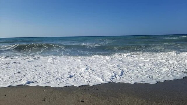 Slow motion footage of foaming waves crashing noisily on a sandy beach on the island of Crete in Greece in august 2023