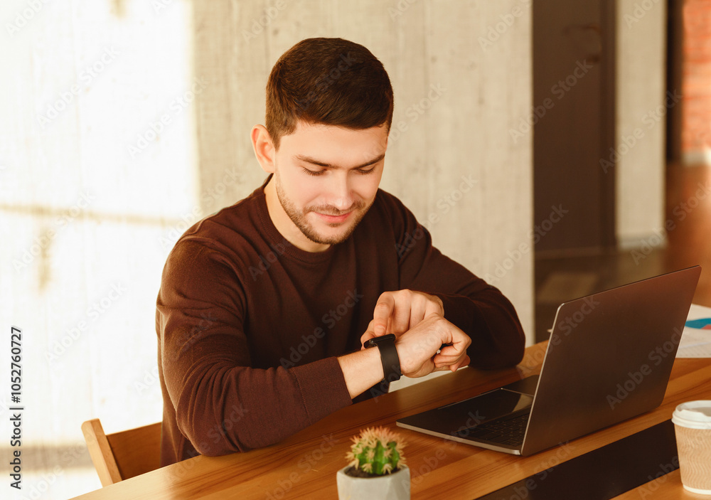Poster working hours. office worker guy at laptop checking time sitting at work desk in modern office. sele