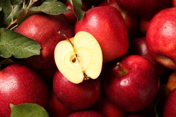 Fresh ripe red apples and green leaves as background, closeup