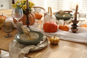 Stylish table setting with beautiful dishware, glasses and autumn decor in dining room