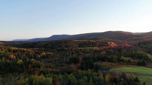 Sunrise along Cape Clear, Cape Breton. Autumn Fall Foliage aerial top view.  Cabot Trail. Mixed forest, deciduous trees with orange and yellow leaves. Fall colors. Cape Breton, Nova Scotia, Canada 