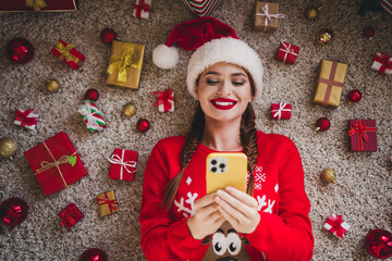 Above view portrait of nice young woman lying floor use phone wear sweater new year xmas time flat...