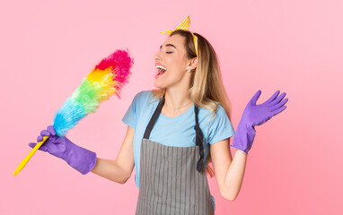 House cleaning with fun. Happy housewife in apron and rubber gloves singing in multicolored brush