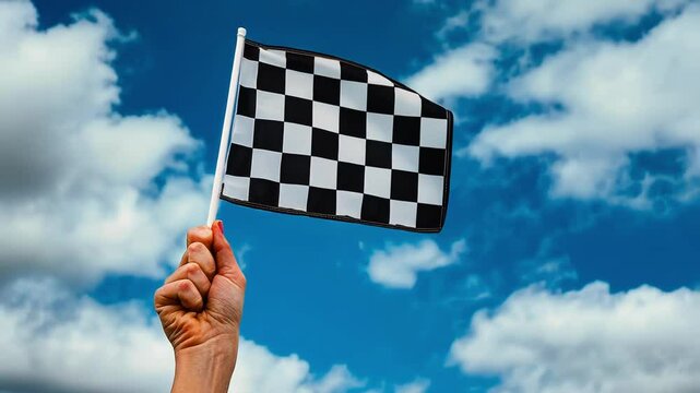 Hand Waving Checkered Flag Against Blue Sky