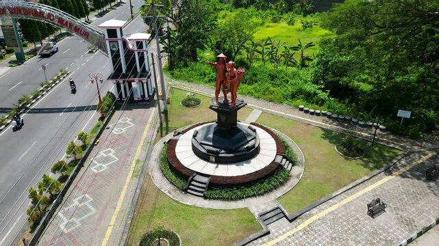 The Jamu statue at Sukoharjo's entrance symbolizes the region's herbal heritage. Surrounded by greenery, it warmly welcomes visitors with its vibrant design.