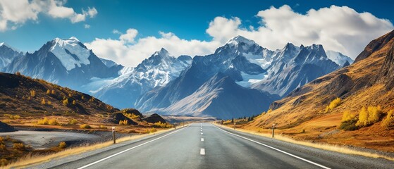 Scenic road leading to majestic mountains under a blue sky.