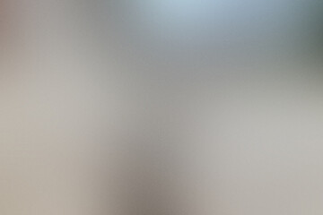 A blurry image of a silver surface with a grey background. Noisy backdrop with grain