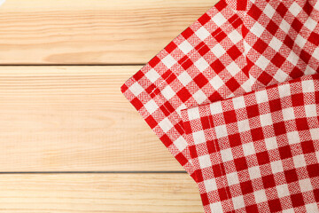 Obraz premium Folded tablecloth with checkered pattern on light wooden table, top view. Space for text