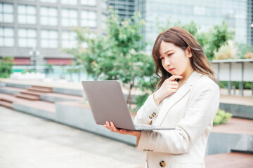 ノートパソコンを持つビジネスウーマン（困る）
