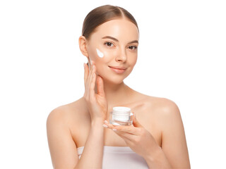 Close-up portrait of young attractive female applying face cream from jar after shower
