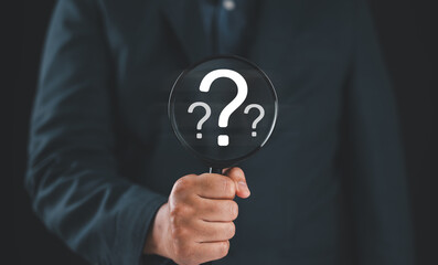 Question mark, Problem solving and analysis concept. Businessman holds magnifying glass focused on...
