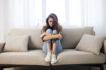 Obraz premium Lonely Woman, Stressed and Depressed, Sitting on Couch, Feeling Sad and Worried, Mental Health at Home.