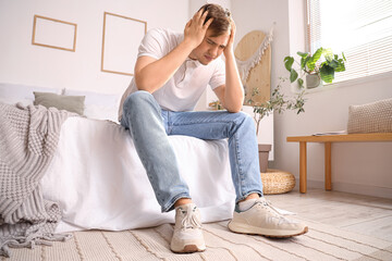 Young man suffering from headache in bedroom